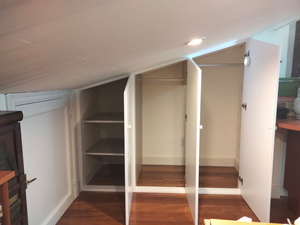 Interior abierto de armario. Compartimentos para colgar y guardar, con cajoneras interiores.