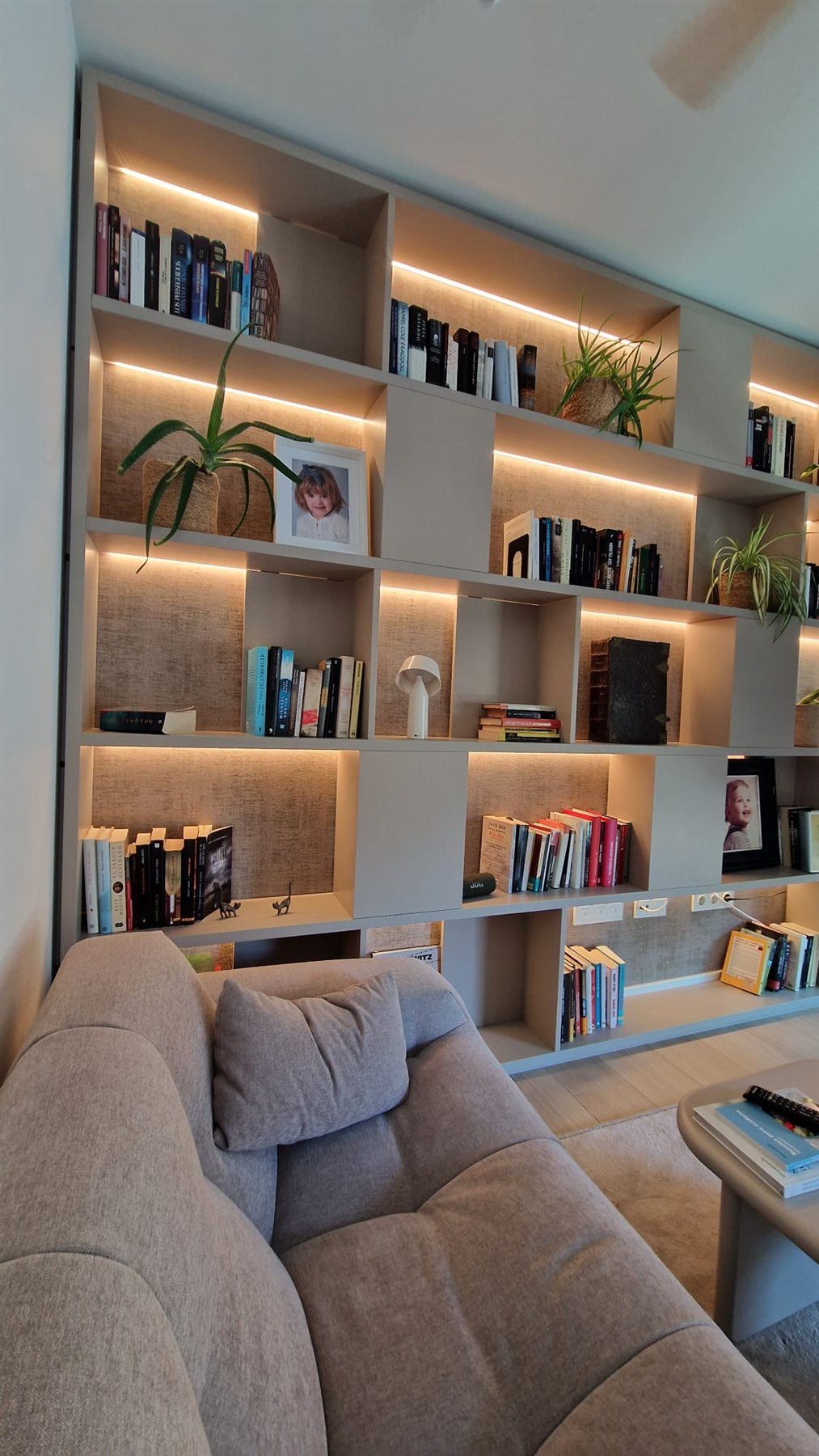 Biblioteca con iluminación. Estantería de salón integrada en el espacio.