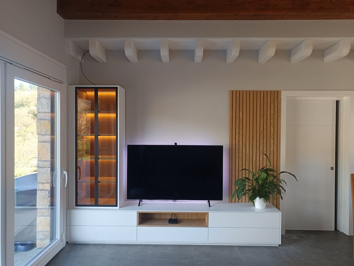 Mobiliario y panelado de salón. Vitrina, mueble bajo y panelado junto a una puerta interior.