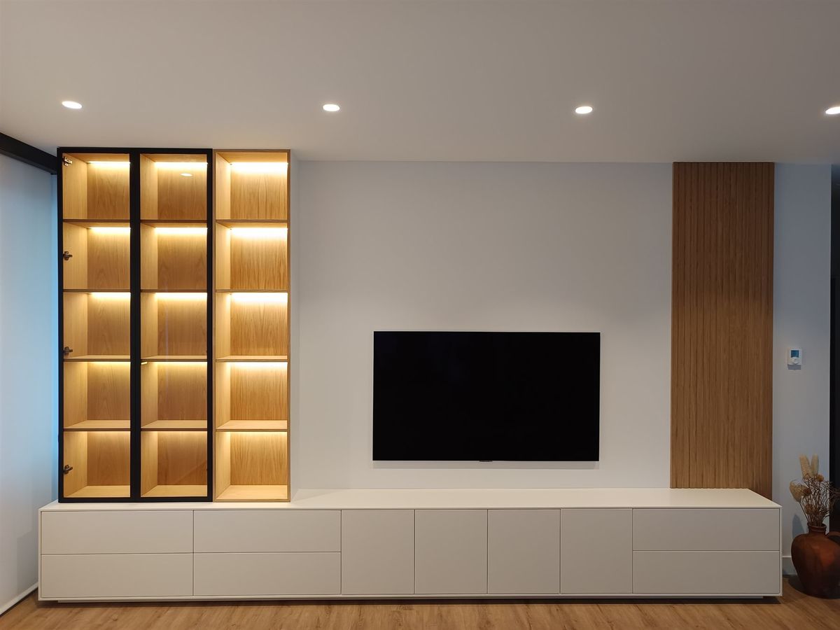Salón con vitrina iluminada. Mueble bajo, vitrina con iluminación y panelado de pared.