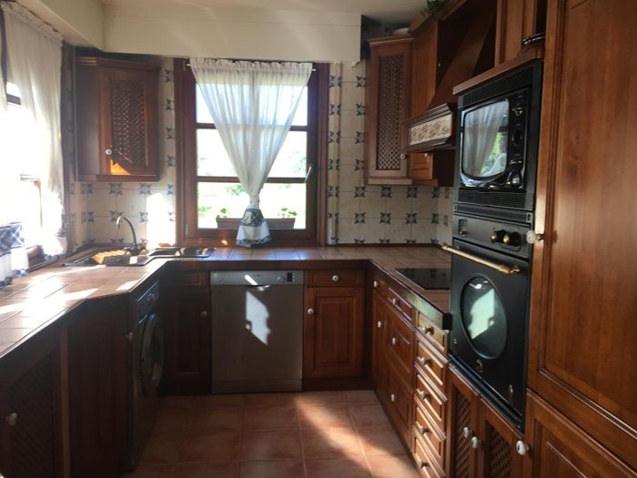 Înainte: bucătărie cu fronturi din lemn închis.